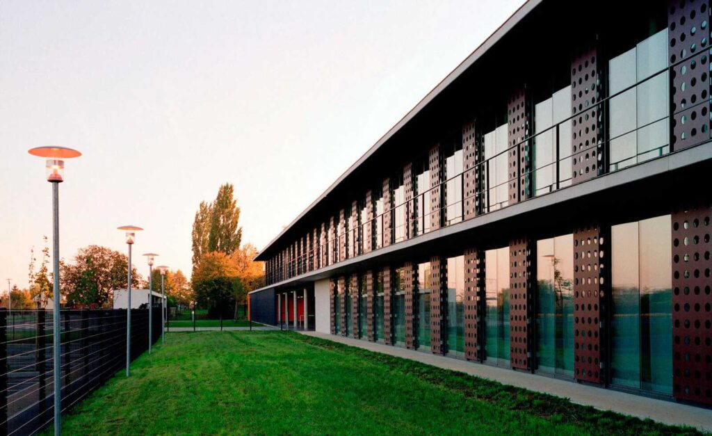 Façade moderne vitrée avec panneaux perforés au coucher du soleil