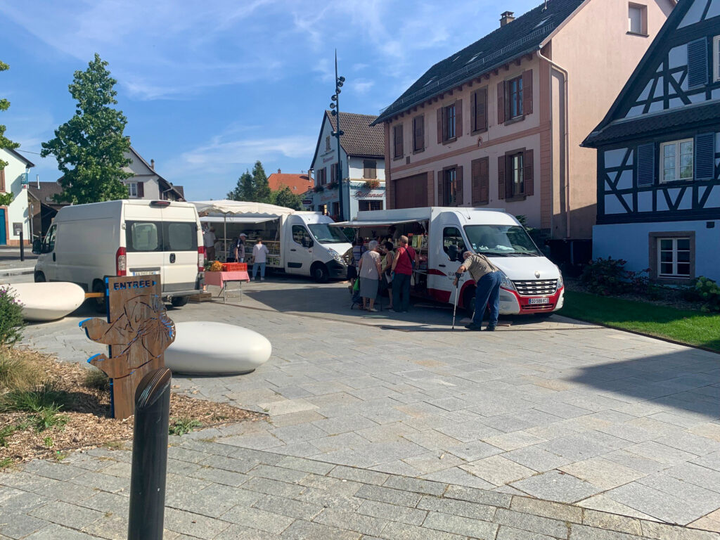 Marché de village avec camionnettes et habitants
