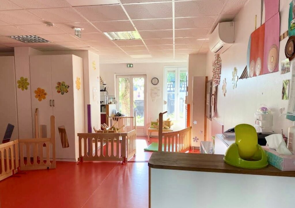 Dortoir de crèche avec lits à barreaux et sol rouge vif