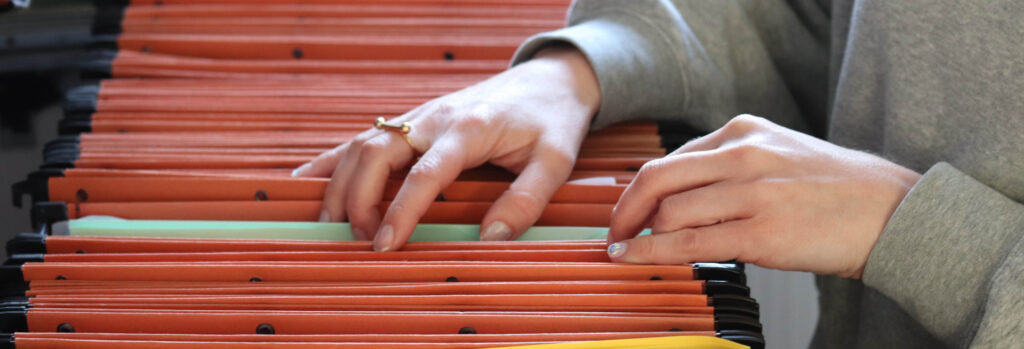 Mains feuilletant dossiers suspendus dans tiroir d'archives