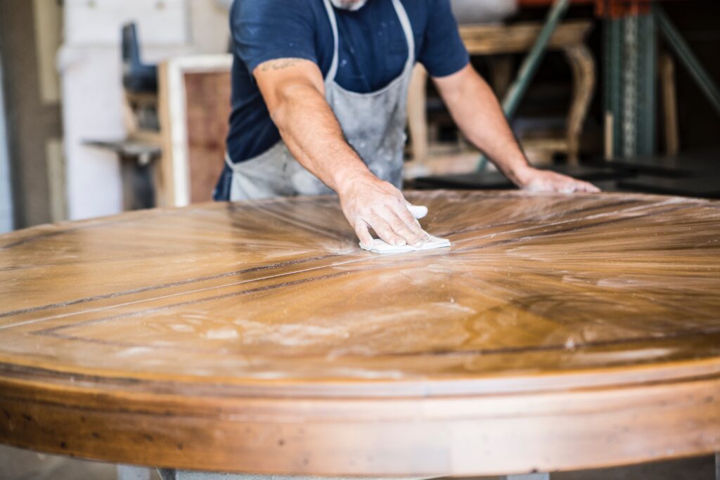 Artisan ponçant une table ronde en bois